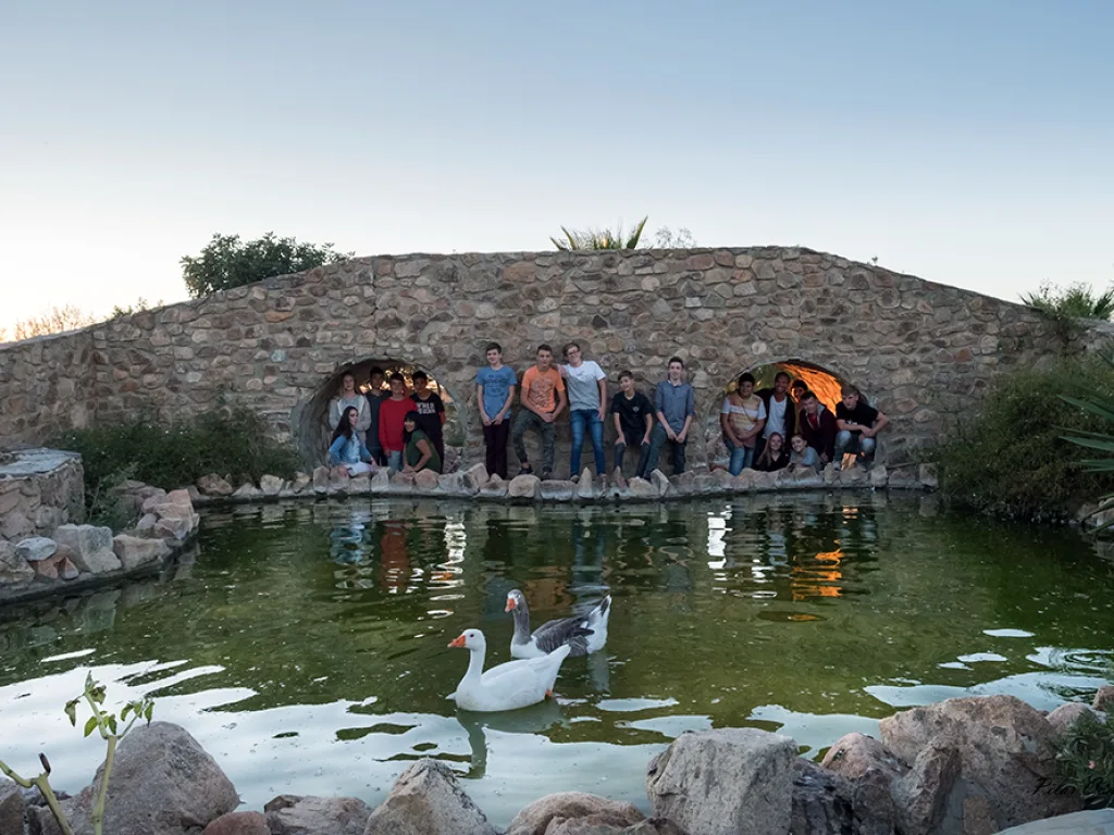 Die Gruppe steht auf der Brücke, im Teich davor schwimmt ein weißer Vogel.